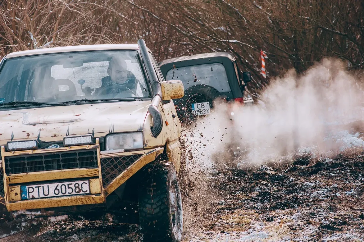 Nowoczesny szary SUV zaparkowany na malowniczej górskiej drodze w świetle zachodzącego słońca.