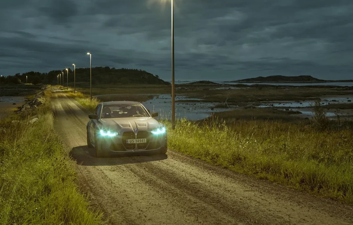 Srebrne BMW serii 3 Gran Turismo zaparkowane na nadmorskiej drodze podczas zachodu słońca, podkreślające jego sylwetkę.