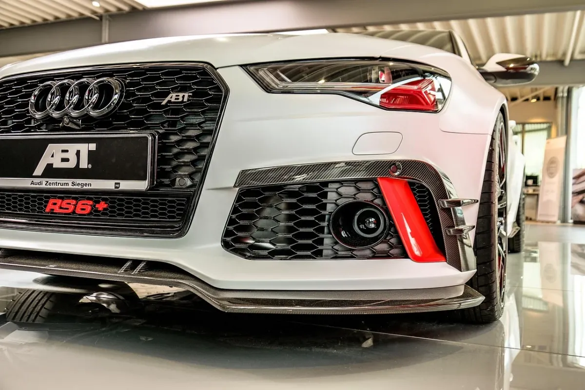 Audi RS6 GT zaparkowane na mokrym torze wyścigowym o zmierzchu, prezentujące sportową stylistykę i karbonowe detale.